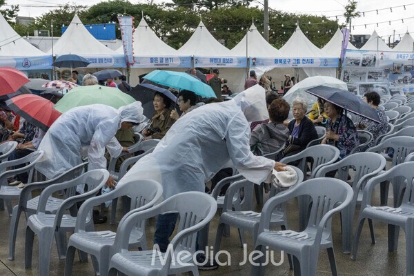 27일 오전 화북포구문화제 주최측에서 의자에 고인 빗물을 지속적으로 닦아내고 있는 모습. /사진=미디어제주.